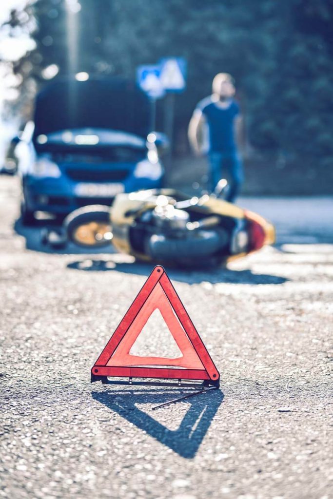 a road flag in front of a car and motorcycle accident on the road