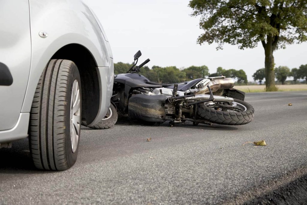 a motorcycle on the ground with a car right after a collision