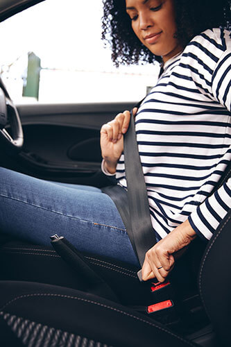 a woman in a car putting on her seat belt 