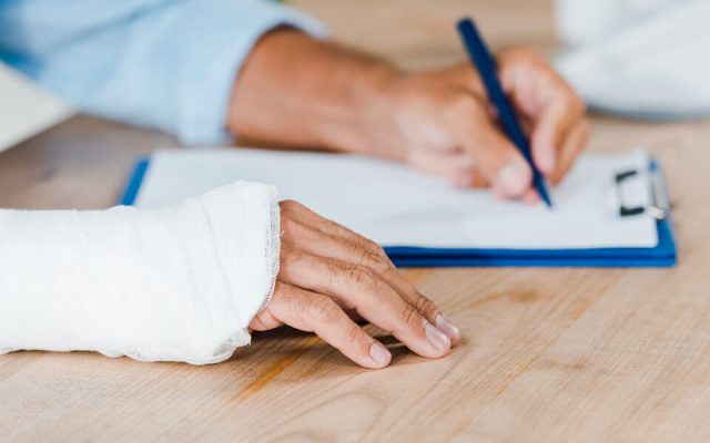 man in wrist cast signing contract with workplace injury lawyers