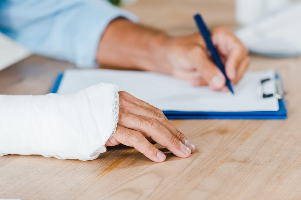 man in wrist cast signing contract with workplace injury lawyers