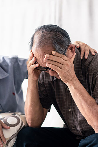 Elderly man with his head in his hands after suffering an injury.