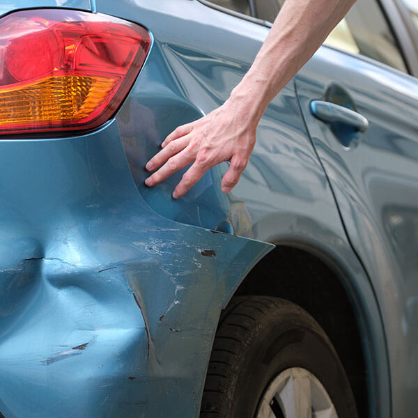 man inspecting car with dented fender needs car accident attorney in Kansas city mo