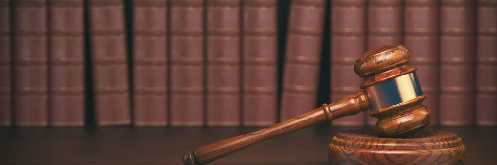 A gavel in front of a row of books.